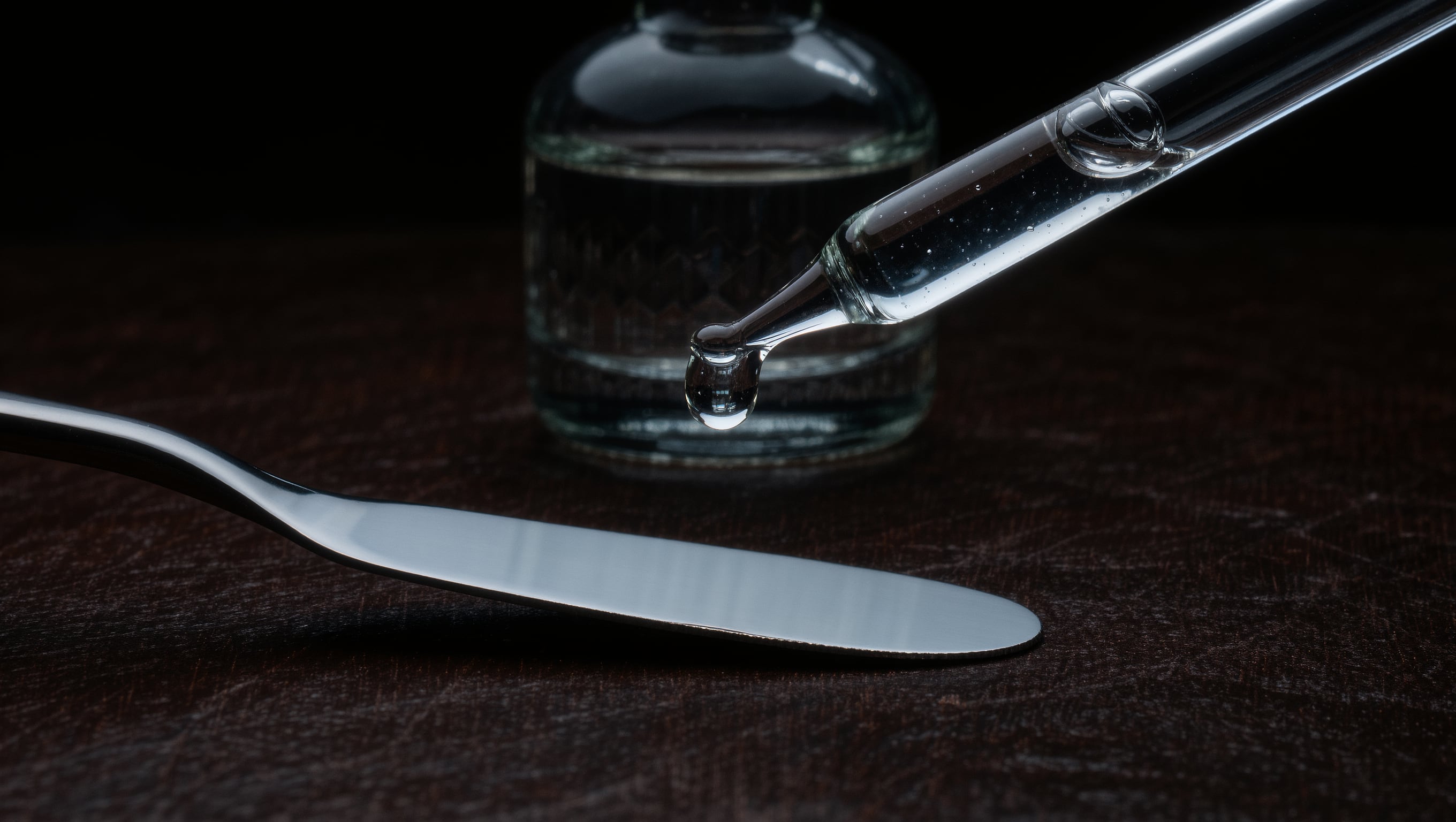 Kosmetikschale mit angerührtem Enzympeeling und Spatel neben gefalteten Tüchern und einer Serumpipette auf heller Behandlungsablage